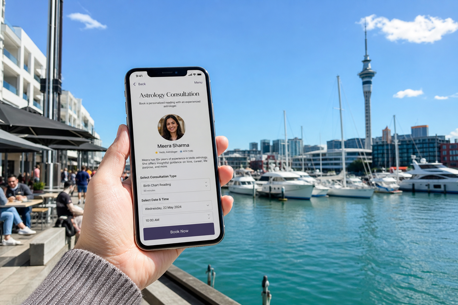 Sunny Auckland waterfront with a smartphone showing an astrology consultation booking screen